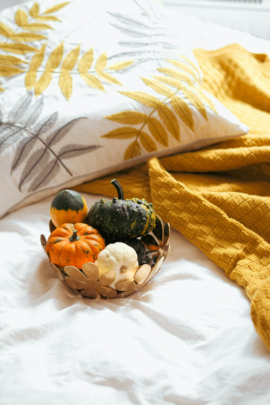 a basket filled with gourds sitting on top of a bed