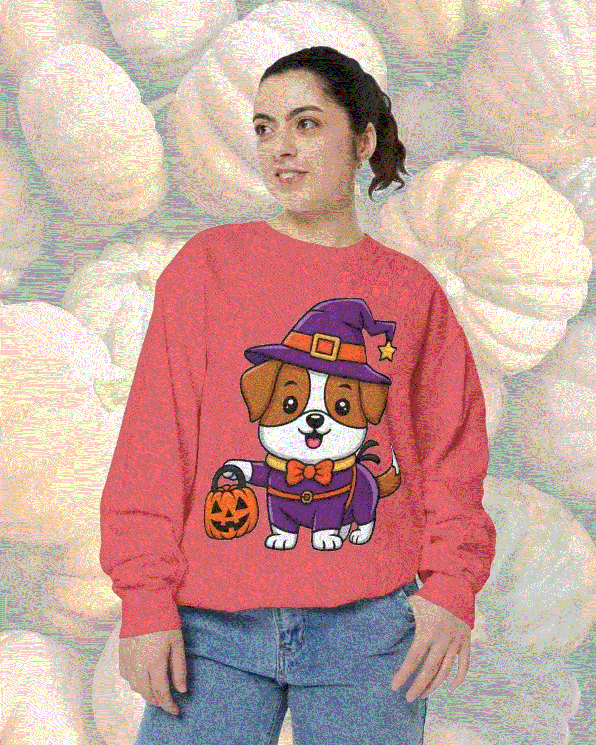 Woman wearing a red sweatshirt featuring a cute dog in a Halloween witch costume holding a pumpkin bucket against a pumpkin background, Halloween Dog Trick or Treating Sweatshirt design.