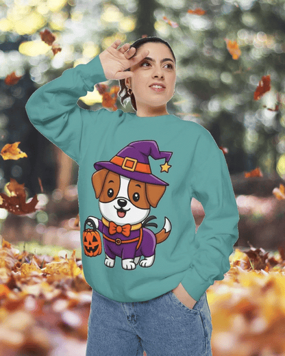 Person wearing teal Halloween sweatshirt with cartoon dog in witch costume holding pumpkin bucket, autumn leaves background