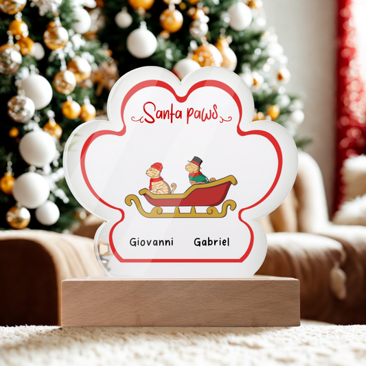 Acrylic paw print Christmas plaque with personalized pet names and LED wooden base in festive room.