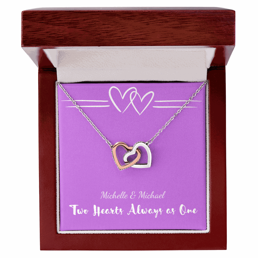 Interlocking Hearts necklace with two interwoven heart pendants in polished metal displayed in a wooden gift box with purple background