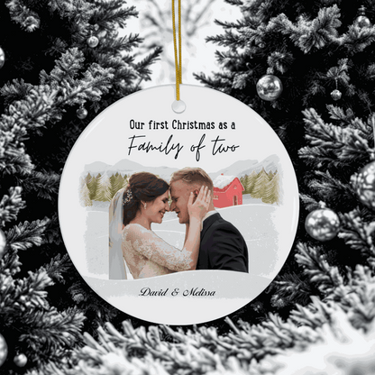 First Christmas Family Ornament personalized with couple photo and names, hanging on snowy Christmas tree branch