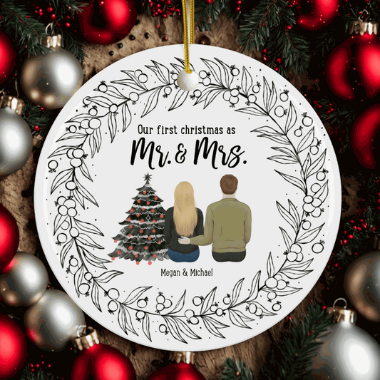 Customizable "Our First Christmas as Mr and Mrs" round ornament with a couple sitting by a decorated Christmas tree and a wreath design on a festive tree background